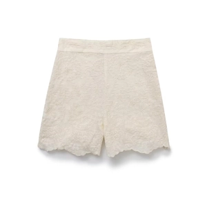Détail des bords festonnés et de la broderie florale sur un short taille haute crème