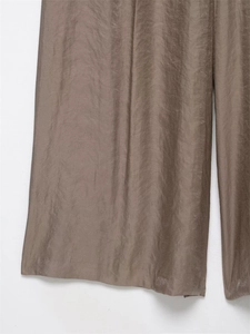 Detail shot of taupe satin wide leg trousers showing silky texture and elegant drape