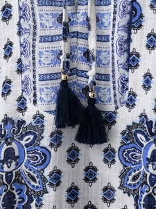Macro detail of blue paisley print on fabric with tassels and gold bead ties