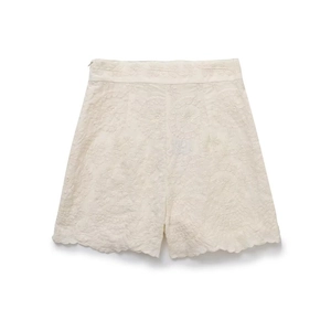Détail d'un short beige à taille haute avec broderie florale et ourlets festonnés élégants
