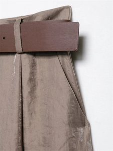 Detail of satin brown high-waisted trousers with matching wide leather belt and side pockets