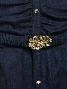Detailaufnahme von gerafftem Jeanskleid mit goldener Blumenschnalle und Silberknöpfen