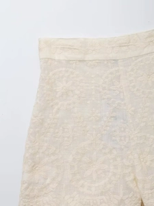 Détail de la taille haute d'une jupe crème avec broderie florale circulaire et couture