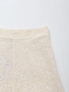 Détail du tissu en coton et lin crème avec broderie florale et motifs ajourés élégants