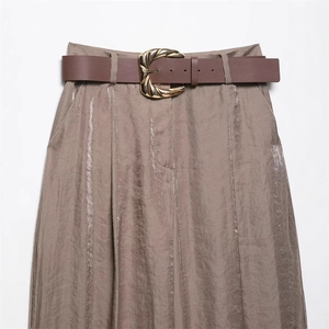 Detail of satin wide leg trousers with a wavy gold buckle belt and vertical texture