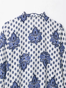 Detail of blue paisley pattern on white linen dress with ruffled high neckline