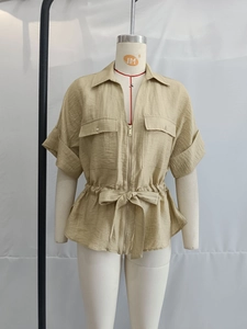 Detail of khaki short sleeve utility shirt showing zipper, waist tie and textured fabric