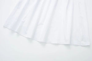 Detailed close-up of white poplin dress hem showing fine stitching and cotton texture