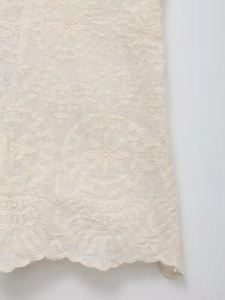 Détail de la broderie florale crème et de l'ourlet festonné sur le tissu doux