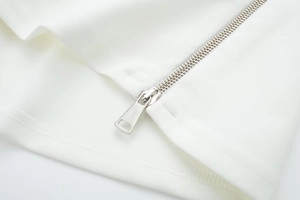 Close-up of sleek silver metal zipper on white fabric with precise stitching detail