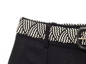 Close-up of black linen dress waist featuring a woven herringbone belt and leather buckle