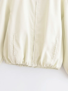 Detail view of cream lightweight jacket with smooth zipper and elastic hem design