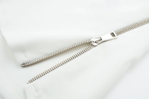 Detailed macro view of high-quality silver metal zipper on white spring jacket