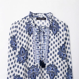 Detail of ruffled stand collar and V-neckline with blue tassels on paisley blouse