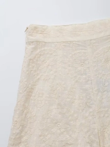Détail d'une jupe blanc crème avec broderie florale et fermeture éclair invisible