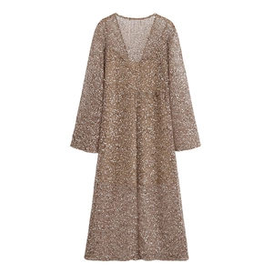 Détail du tissu en maille à paillettes champagne sur une robe de soirée à manches longues