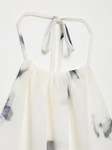 Dettaglio del top allacciato al collo in chiffon bianco con motivo a inchiostro e coulisse