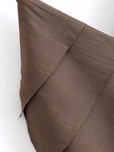 Close-up of deep brown textured fabric with silk sheen and neat overlocked edge detail