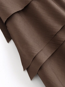 Detailed macro view of dark brown satin fabric showing layered texture and subtle silk sheen