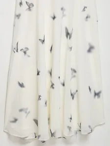 Dettaglio dell'abito in chiffon bianco con stampe artistiche di farfalle nere sfumate