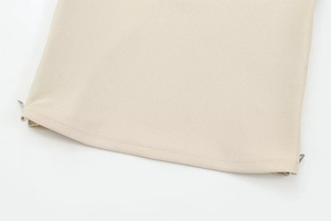 Close-up detail of beige twill fabric hem featuring silver metal zipper accessories