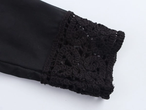 Detailed close-up of intricate crochet embroidery on black long sleeve shirt cuffs