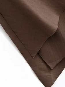 Close-up of layered dark coffee fabric showing thick texture and smooth drape