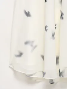 Dettaglio dell'orlo dell'abito in chiffon bianco con stampe di farfalle sfumate