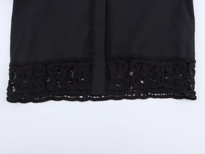 Detail of black woven shirt hem featuring intricate crochet lace hollow-out patterns