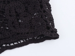 Detailed macro view of black crochet knit fabric featuring intricate hollow floral patterns