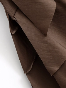 Macro detail of dark brown tiered dress fabric showing high-quality stitching and texture