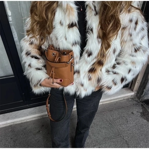 Close-up of brown pebbled leather bucket bag styled with a leopard print faux fur coat