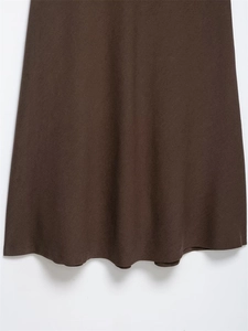 Gros plan sur la texture du tissu en laine marron foncé et le drapé en A d'une jupe