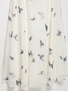 Dettaglio dell'abito in chiffon bianco avorio con stampa artistica di farfalle nere
