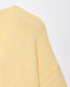 Close-up of the light yellow knit cardigan featuring v-neck detail and soft mesh texture