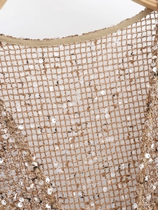 Gros plan d'une robe en maille à paillettes champagne avec détails ajourés délicats