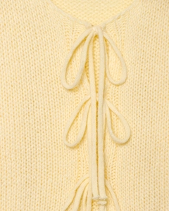 Detailed close-up of soft yellow knit sweater cardigan with delicate tie-up front design