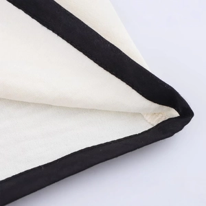 Close-up of contrast black binding on cream crepe top with detailed stitching and texture