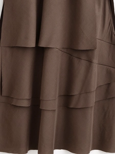 Close-up of dark brown tiered dress showing layered design and fine fabric texture