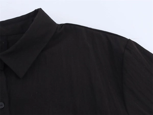 Detail view of black double-layered cotton shirt showing sharp collar and neat stitching