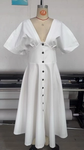 Detail of white V-neck dress featuring contrasting black buttons and cinched waistline