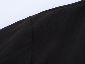 Detailed close-up of double-layer black shirt seams with fine stitching and matte texture