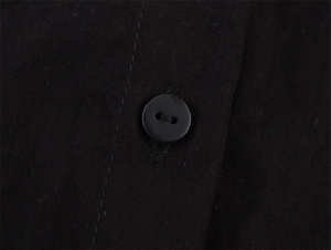 Macro shot of black shirt fabric texture and neat stitching around a resin button
