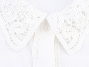 Close-up of intricate crochet lace collar and small button detail on white shirt