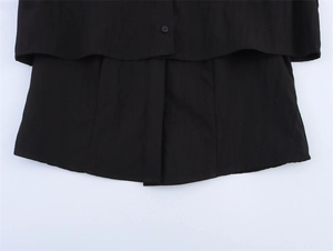 Close-up of black double-layered shirt hem with matching small buttons and plain weave texture