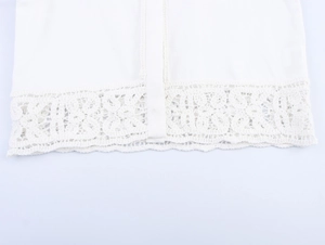 Detail of white shirt hem featuring intricate floral lace crochet and embroidery trim