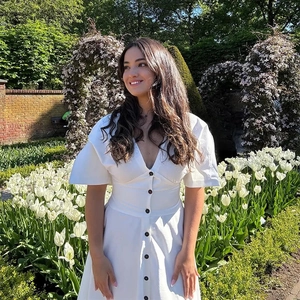 Elegant white V-neck dress with dark button accents and a flattering cinched waistline