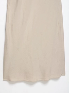 Macro detail of silky beige satin midi dress showing smooth fabric texture and hemline