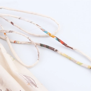 Detail shot of spaghetti straps and colorful floral print on cream-colored fabric