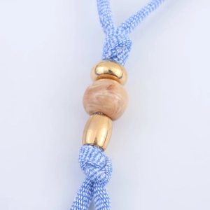 Detail of blue and white braided lanyard with marble resin bead and gold metal beads